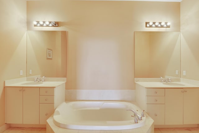 bathroom featuring tile patterned flooring, two vanities, a sink, and a bath