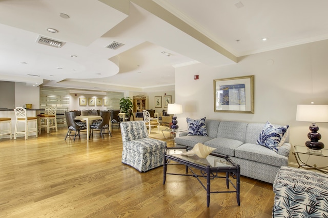 living room with ornamental molding, visible vents, and wood finished floors