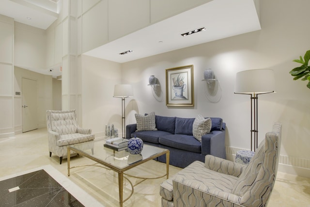 living area with a towering ceiling, granite finish floor, visible vents, and baseboards