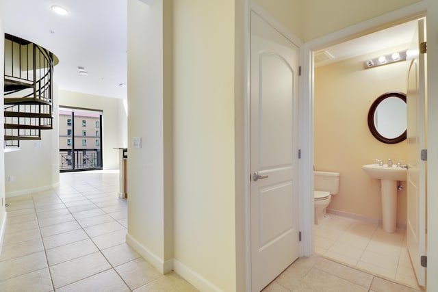 corridor with light tile patterned floors, stairway, and baseboards