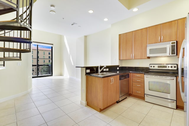 kitchen with visible vents, dark countertops, appliances with stainless steel finishes, a peninsula, and a sink