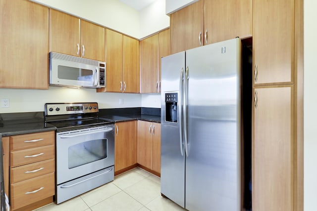 kitchen with appliances with stainless steel finishes, dark countertops, and light tile patterned floors