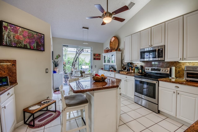6861 Briarlake Cir, Palm Beach Gardens, FL 33418 - kitchen with stainless steel appliances, tasteful backsplash, white cabinetry, a breakfast bar, and dark stone counters