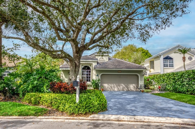 view of front of home with decorative driveway, a tiled roof, an attached garage, and stucco siding