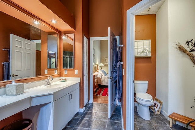 ensuite bathroom with baseboards, connected bathroom, toilet, tile patterned floors, and vanity