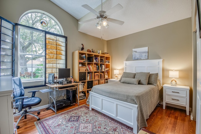 bedroom with lofted ceiling, a textured ceiling, a ceiling fan, and wood finished floors