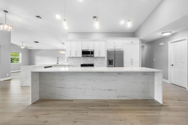 kitchen featuring a sink, visible vents, white cabinets, vaulted ceiling, and appliances with stainless steel finishes