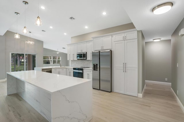 kitchen with lofted ceiling, visible vents, white cabinetry, appliances with stainless steel finishes, and decorative backsplash