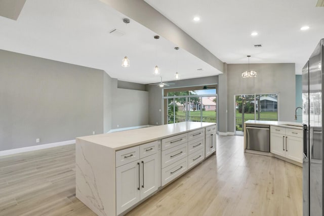 kitchen featuring stainless steel appliances, open floor plan, light wood-style flooring, and baseboards