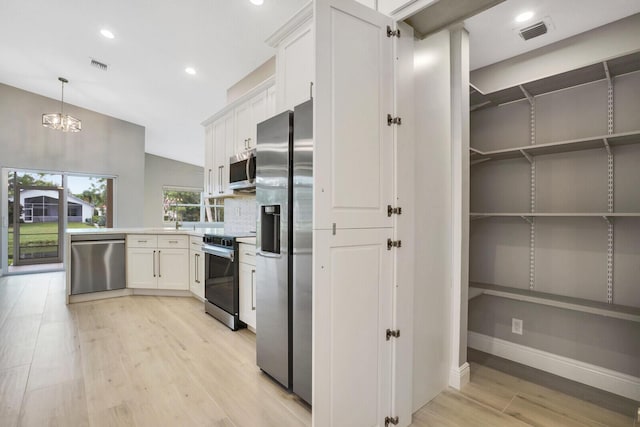 kitchen with a peninsula, light wood-style floors, visible vents, and appliances with stainless steel finishes