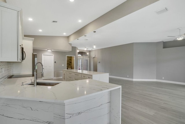 kitchen with arched walkways, a sink, visible vents, baseboards, and stainless steel microwave