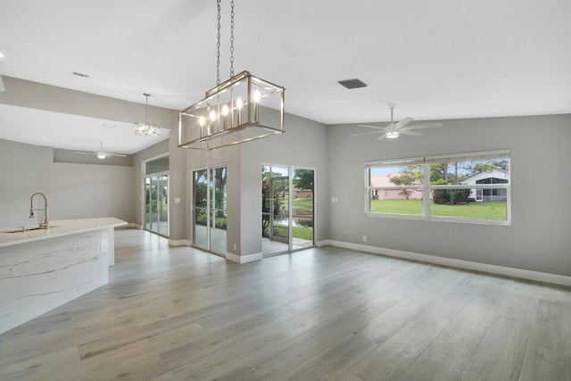 unfurnished living room with ceiling fan, light wood-style flooring, a sink, and visible vents