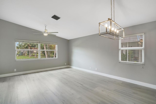 spare room with baseboards, visible vents, lofted ceiling, wood finished floors, and ceiling fan with notable chandelier