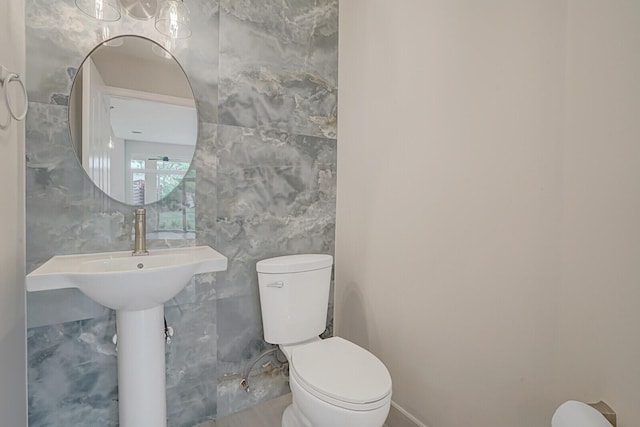 half bathroom with toilet and tile walls