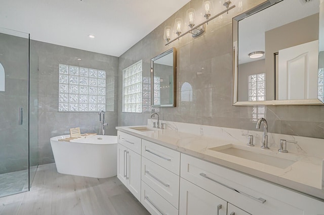 bathroom featuring a sink, a stall shower, and tile walls