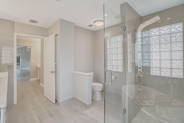 full bathroom featuring a wealth of natural light, a stall shower, wood finished floors, and visible vents