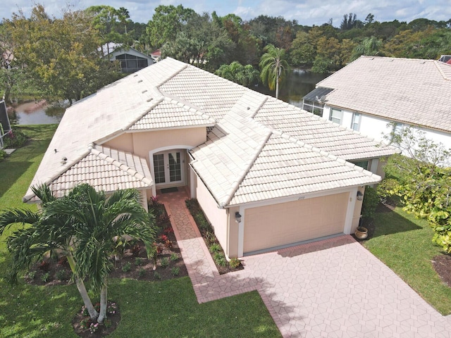 view of front of property featuring an attached garage, stucco siding, a tiled roof, and french doors