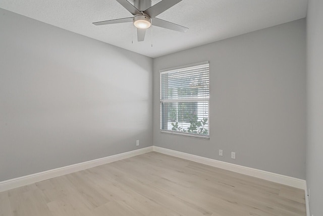 empty room featuring light wood-style flooring, baseboards, ceiling fan, and a textured ceiling