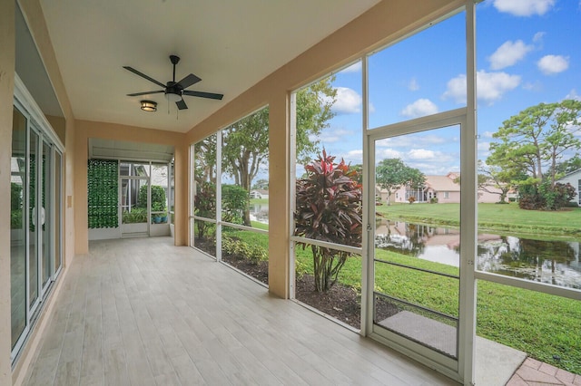 unfurnished sunroom featuring ceiling fan, a water view, and plenty of natural light