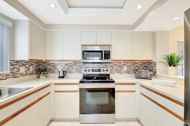 kitchen featuring stainless steel appliances, a raised ceiling, decorative backsplash, and light tile patterned floors