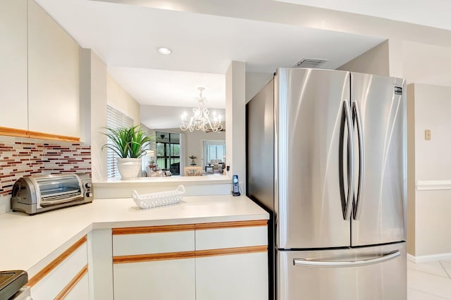 kitchen with freestanding refrigerator, light countertops, decorative backsplash, and light tile patterned flooring