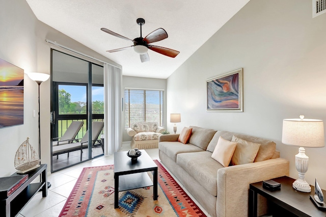 living room featuring a ceiling fan, lofted ceiling, visible vents, and light tile patterned floors