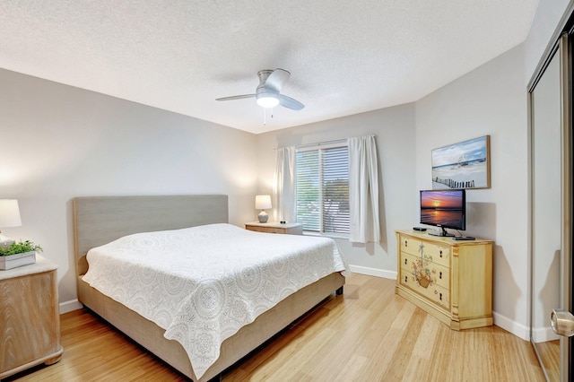 bedroom featuring a textured ceiling, light wood finished floors, a ceiling fan, and baseboards