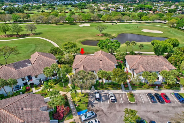 drone / aerial view featuring golf course view, a water view, and a residential view