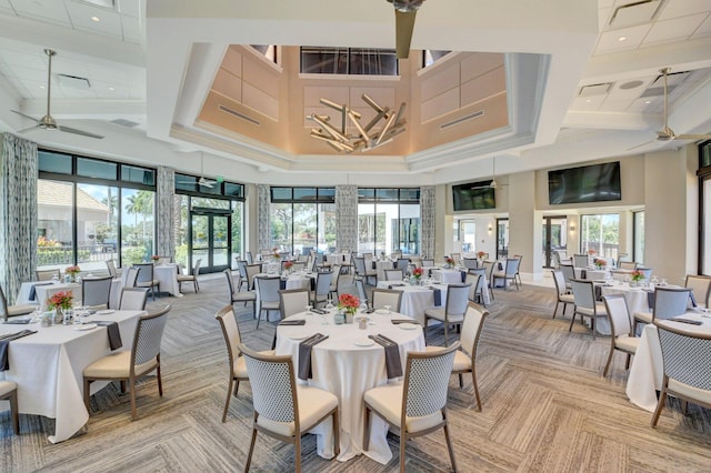 dining area featuring plenty of natural light, a towering ceiling, and ceiling fan with notable chandelier