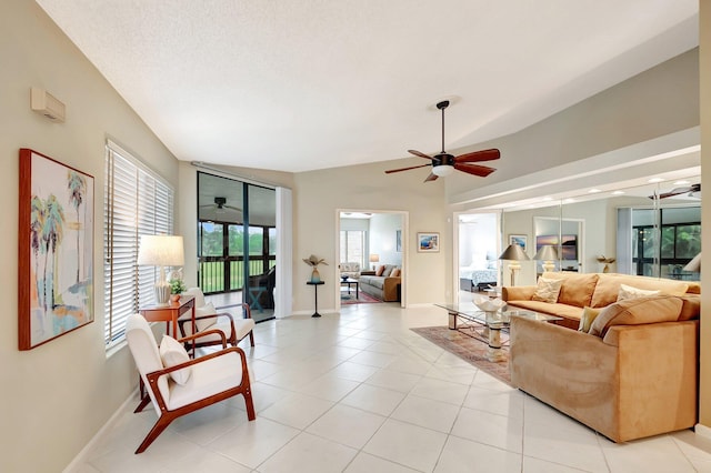 living area with light tile patterned floors, vaulted ceiling, a ceiling fan, and baseboards