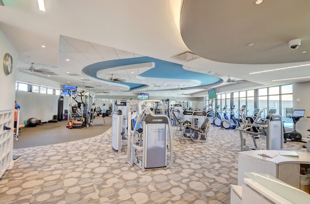 workout area featuring carpet floors, ceiling fan, a tray ceiling, and recessed lighting