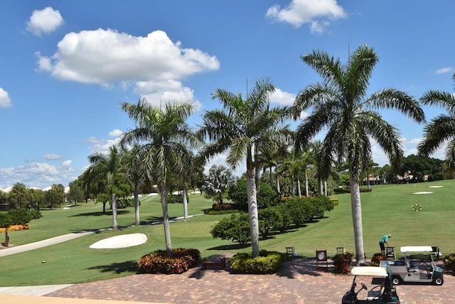 view of property's community with view of golf course and a yard