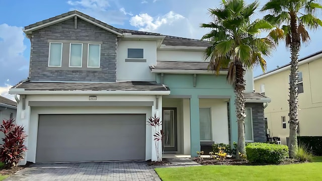 view of front facade with decorative driveway, stone siding, and stucco siding