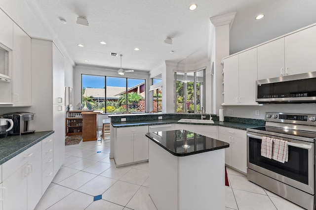 kitchen featuring light tile patterned flooring, stainless steel appliances, a peninsula, a sink, and a center island