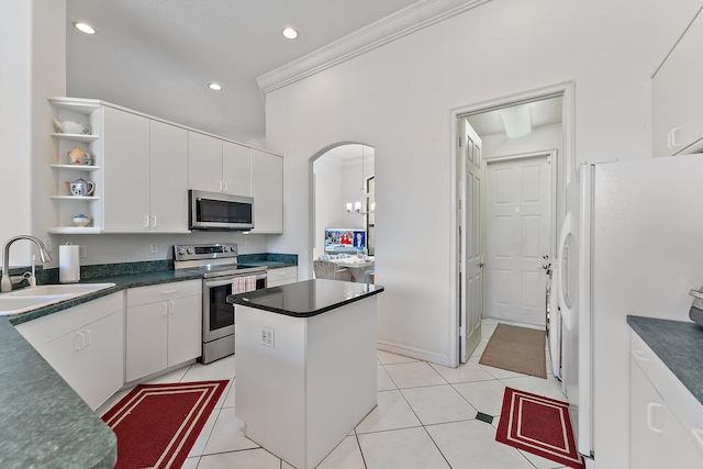 kitchen featuring light tile patterned floors, dark countertops, appliances with stainless steel finishes, open shelves, and a sink