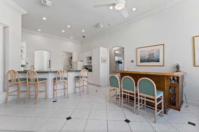 dining room featuring arched walkways, ceiling fan, light tile patterned floors, recessed lighting, and crown molding