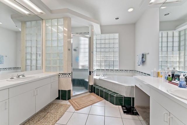 full bathroom featuring tile patterned floors, two vanities, a sink, a shower stall, and a bath