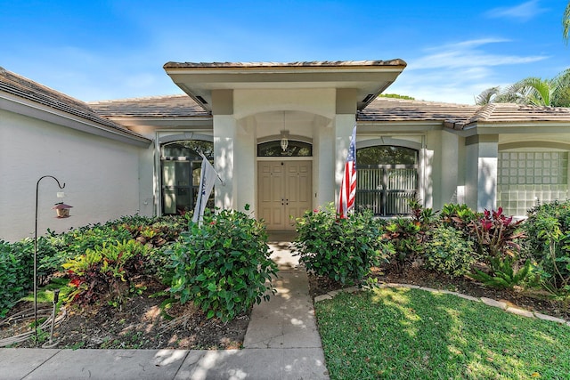 property entrance featuring a tile roof and stucco siding