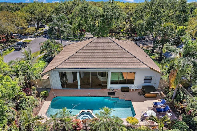 rear view of house with a patio area, a fenced backyard, and a pool with connected hot tub