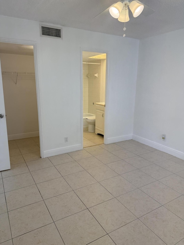 unfurnished bedroom with light tile patterned floors, a closet, a spacious closet, visible vents, and baseboards