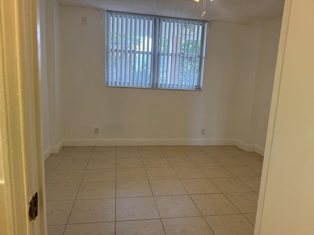 tiled empty room featuring baseboards