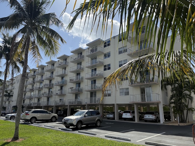 view of building exterior with covered and uncovered parking