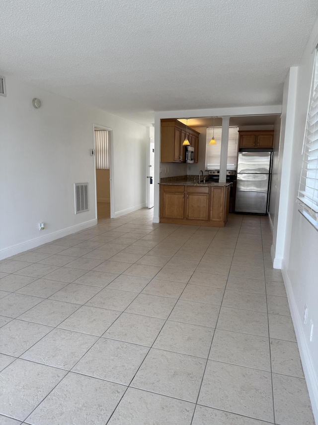 unfurnished living room featuring a textured ceiling, light tile patterned floors, and visible vents