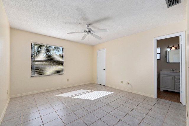 spare room with light tile patterned floors, baseboards, visible vents, and a ceiling fan