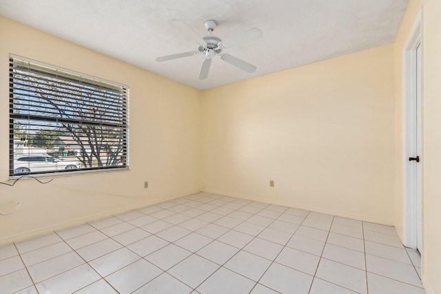 empty room featuring ceiling fan, light tile patterned floors, and baseboards