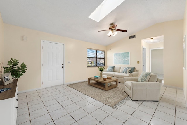 living room with light tile patterned floors, vaulted ceiling with skylight, visible vents, baseboards, and ceiling fan