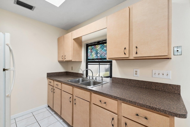 kitchen featuring light tile patterned floors, a sink, visible vents, freestanding refrigerator, and dark countertops