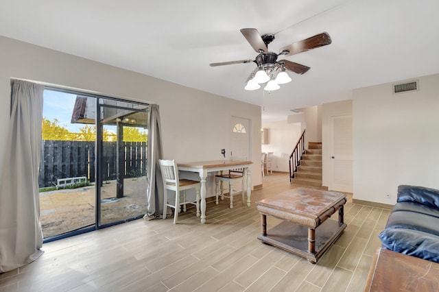 living room featuring visible vents, wood tiled floor, ceiling fan, baseboards, and stairs