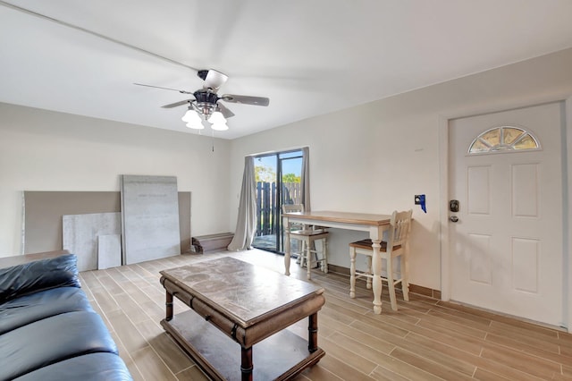 living room featuring wood tiled floor, baseboards, and ceiling fan