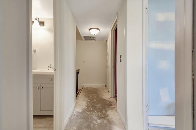 corridor featuring visible vents, baseboards, and unfinished concrete floors